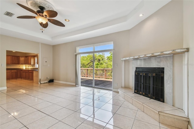 284 Peninsula Ave, Tarpon Springs, FL 34689 - unfurnished living room featuring a tray ceiling, light tile patterned floors, a high end fireplace, ceiling fan, and baseboards