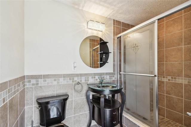 284 Peninsula Ave, Tarpon Springs, FL 34689 - full bathroom with tile walls, a stall shower, a textured ceiling, and a sink