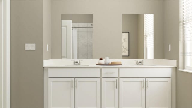 bathroom with a sink, a tile shower, and double vanity