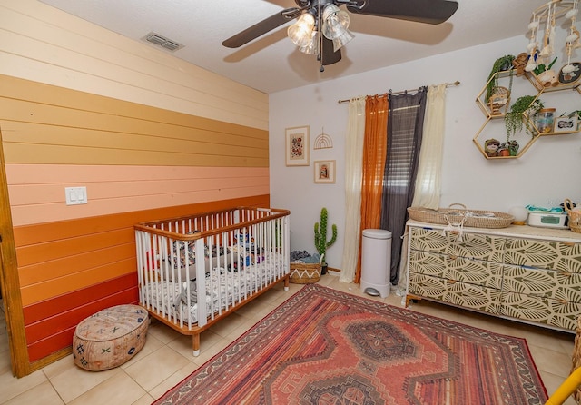 35109 Excalibur, Webster, FL 33597 - tiled bedroom featuring wood walls, a crib, visible vents, and a ceiling fan