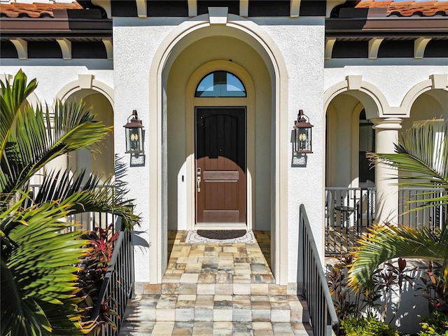 entrance to property featuring a tile roof and stucco siding