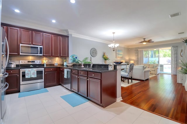 1023 Orca Ct, Holiday, FL 34691 - kitchen with visible vents, reddish brown cabinets, ornamental molding, appliances with stainless steel finishes, and open floor plan
