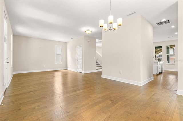 interior space with stairs, a chandelier, visible vents, and hardwood / wood-style floors