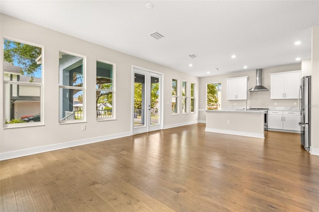 unfurnished living room with visible vents, a wealth of natural light, and wood finished floors