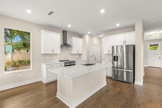 kitchen featuring visible vents, baseboards, wall chimney range hood, a sink, and stainless steel appliances