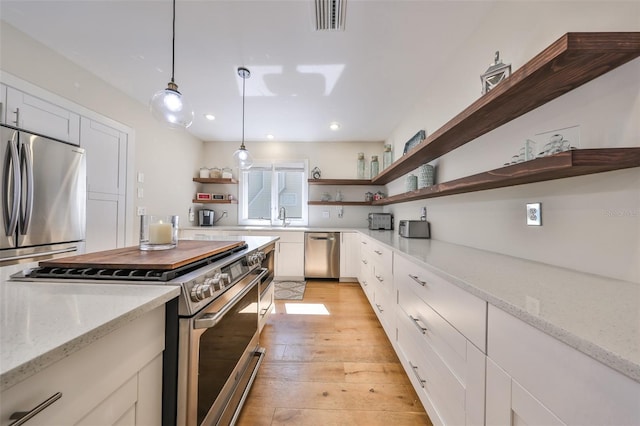 2802 Old Bayshore Way, Tampa, FL 33611 - kitchen with open shelves, appliances with stainless steel finishes, decorative light fixtures, white cabinets, and a sink