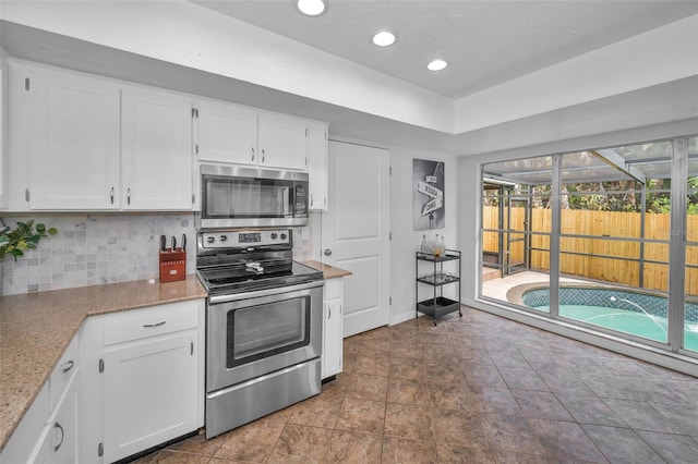 613 Valley Hill Dr, Brandon, FL 33510 - kitchen with appliances with stainless steel finishes, backsplash, white cabinetry, light stone countertops, and recessed lighting