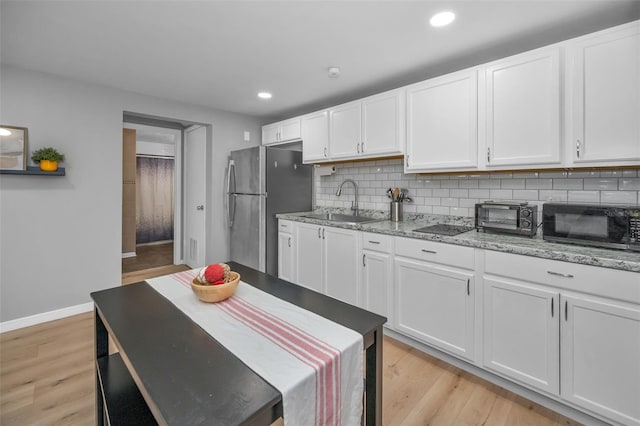 613 Valley Hill Dr, Brandon, FL 33510 - kitchen featuring black microwave, a sink, freestanding refrigerator, white cabinetry, and light wood-style floors