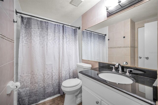 613 Valley Hill Dr, Brandon, FL 33510 - full bath with vanity, toilet, tile walls, a textured ceiling, and tile patterned floors