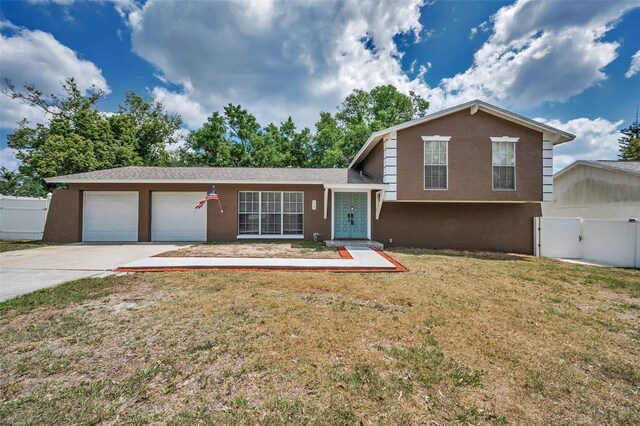 613 Valley Hill Dr, Brandon, FL 33510 - tri-level home with driveway, stucco siding, an attached garage, and a gate