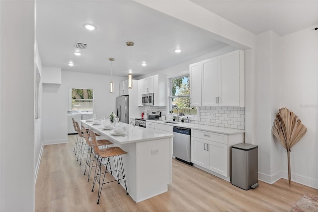 3000 19th Ave S, Saint Petersburg, FL 33712 - kitchen featuring stainless steel appliances, a sink, a breakfast bar area, light wood-style floors, and a kitchen island