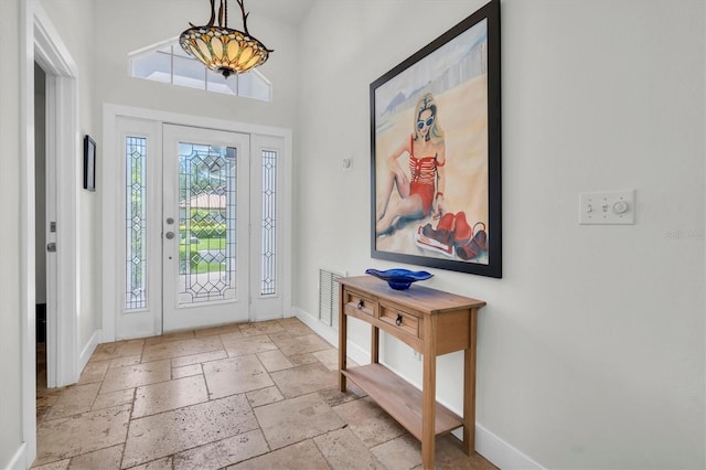 foyer entrance featuring stone tile floors, baseboards, and visible vents