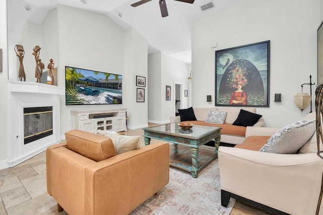 living room featuring a glass covered fireplace, visible vents, high vaulted ceiling, and ceiling fan