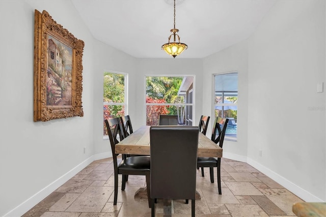 dining space with baseboards and stone tile floors