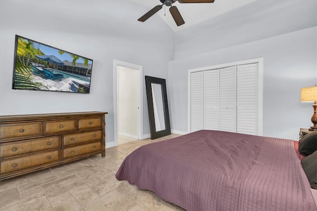 bedroom featuring high vaulted ceiling, a closet, ceiling fan, baseboards, and stone finish floor