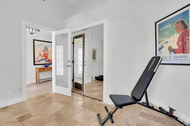 workout area with stone tile floors, baseboards, and french doors