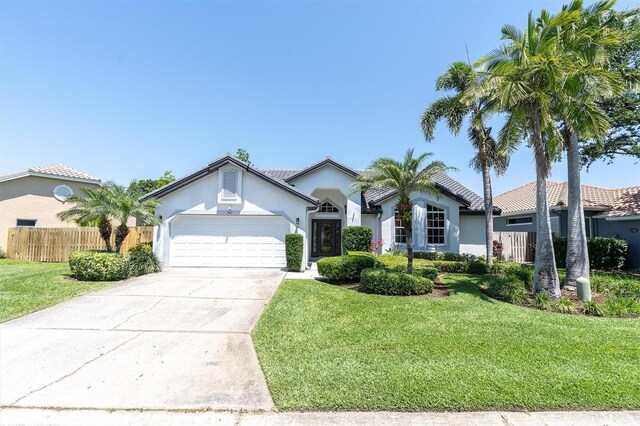 ranch-style house with fence, a front lawn, concrete driveway, stucco siding, and a garage