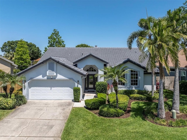 single story home featuring stucco siding, a tile roof, driveway, a front yard, and a garage