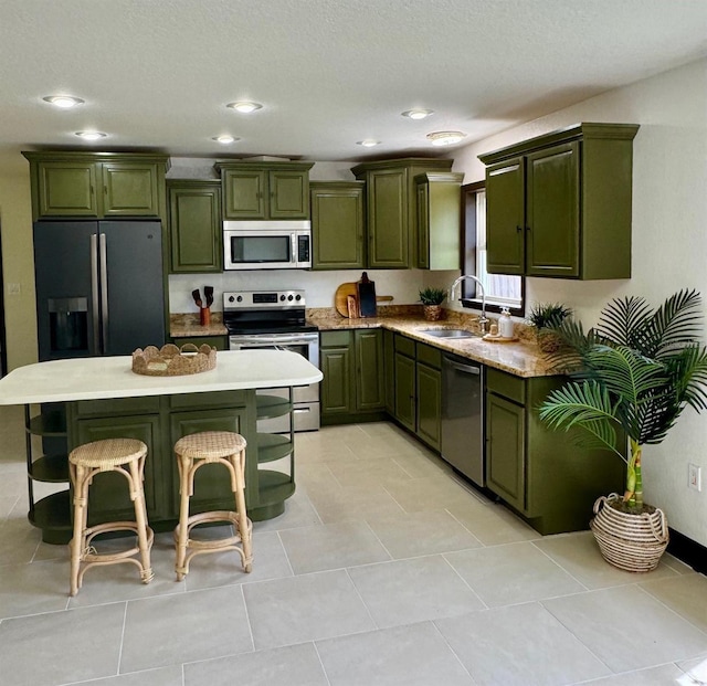 11797 David Ct, Largo, FL 33778 - kitchen featuring green cabinets, stainless steel appliances, a breakfast bar, recessed lighting, and a kitchen island
