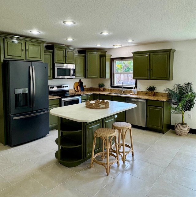 11797 David Ct, Largo, FL 33778 - kitchen featuring green cabinetry, stainless steel appliances, a textured ceiling, a center island, and recessed lighting