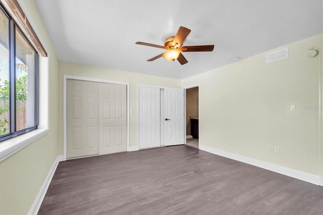 11797 David Ct, Largo, FL 33778 - unfurnished bedroom with two closets, dark wood-style flooring, and a ceiling fan