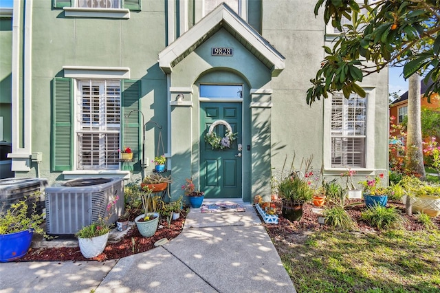 doorway to property with cooling unit and stucco siding