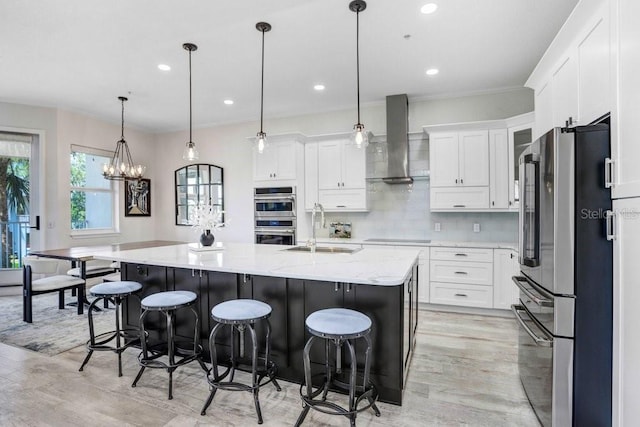 kitchen featuring a sink, a breakfast bar, ventilation hood, light wood-style flooring, and appliances with stainless steel finishes