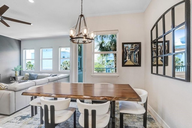 dining space with wood finished floors, crown molding, ceiling fan with notable chandelier, and baseboards