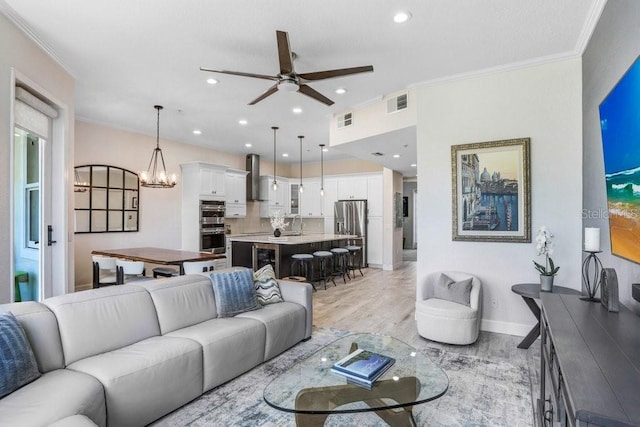 living room with visible vents, crown molding, and ceiling fan with notable chandelier
