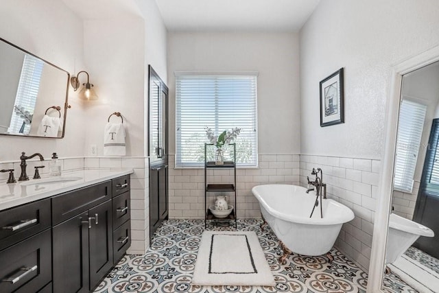 full bath featuring a soaking tub, tile walls, tile patterned floors, vanity, and wainscoting