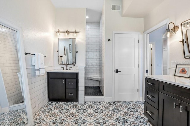 full bathroom with walk in shower, a sink, two vanities, and visible vents