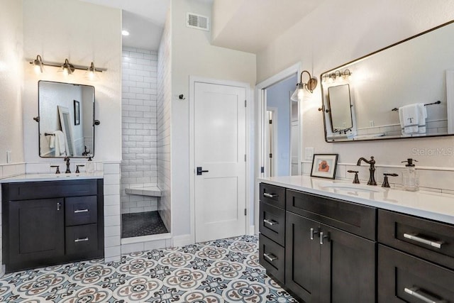 bathroom featuring visible vents, a walk in shower, two vanities, and a sink