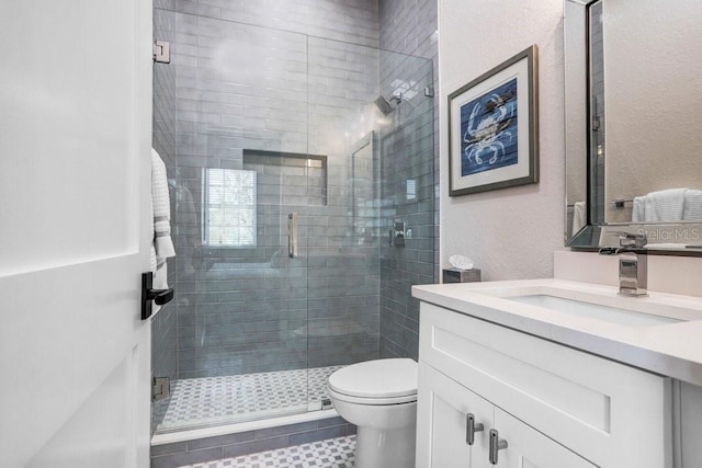 full bathroom with toilet, a stall shower, a textured wall, and vanity
