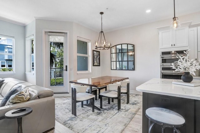 dining space featuring crown molding, light wood finished floors, a chandelier, and a healthy amount of sunlight