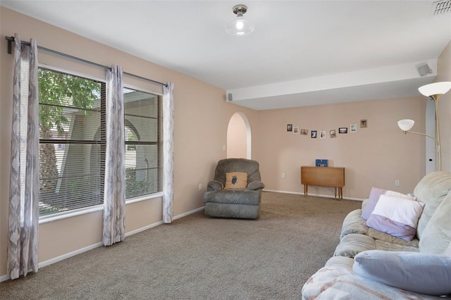 living room with baseboards, arched walkways, visible vents, and carpet