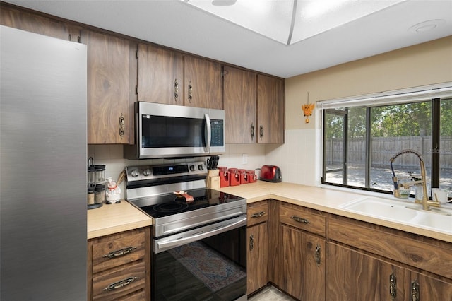 kitchen with light countertops, tasteful backsplash, appliances with stainless steel finishes, and a sink