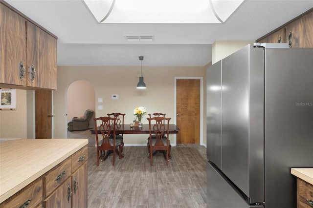 kitchen with brown cabinets, light wood finished floors, light countertops, baseboards, and freestanding refrigerator