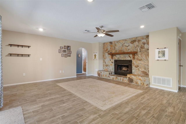unfurnished living room with baseboards, a ceiling fan, visible vents, and arched walkways