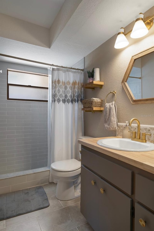 full bathroom featuring toilet, vanity, tile patterned floors, and tiled shower