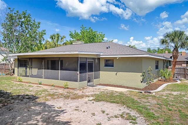 back of property featuring fence, a chimney, a sunroom, and stucco siding