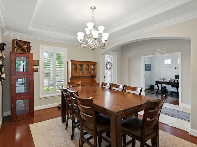 dining room featuring arched walkways, a notable chandelier, wood finished floors, and visible vents