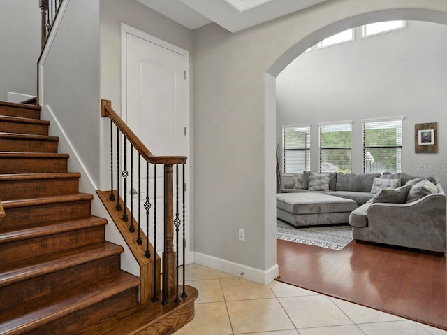 interior space with stairway, arched walkways, baseboards, and light tile patterned flooring