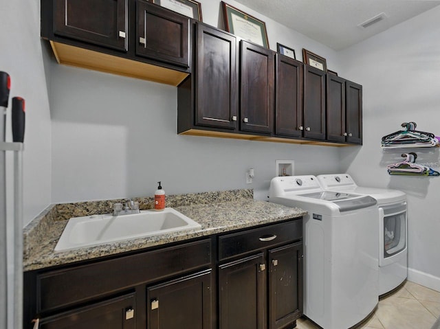 laundry area with visible vents, washing machine and dryer, cabinet space, a sink, and light tile patterned floors