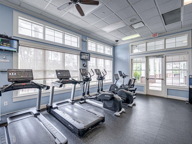 workout area featuring ceiling fan, a paneled ceiling, and a wealth of natural light