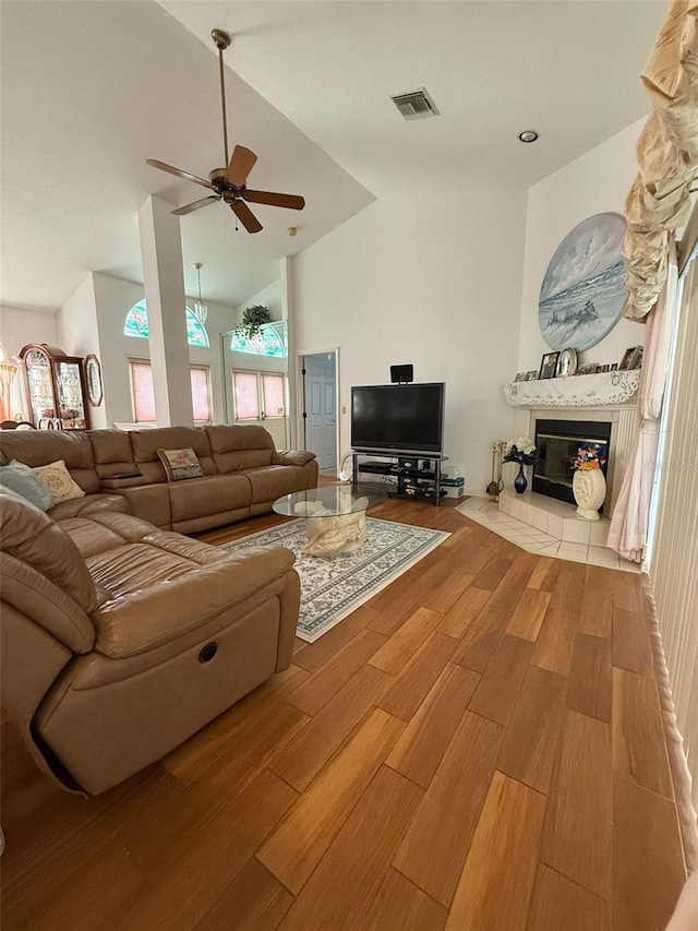 1695 Stable Trl, Palm Harbor, FL 34685 - living room with ceiling fan, visible vents, a tiled fireplace, wood finished floors, and lofted ceiling