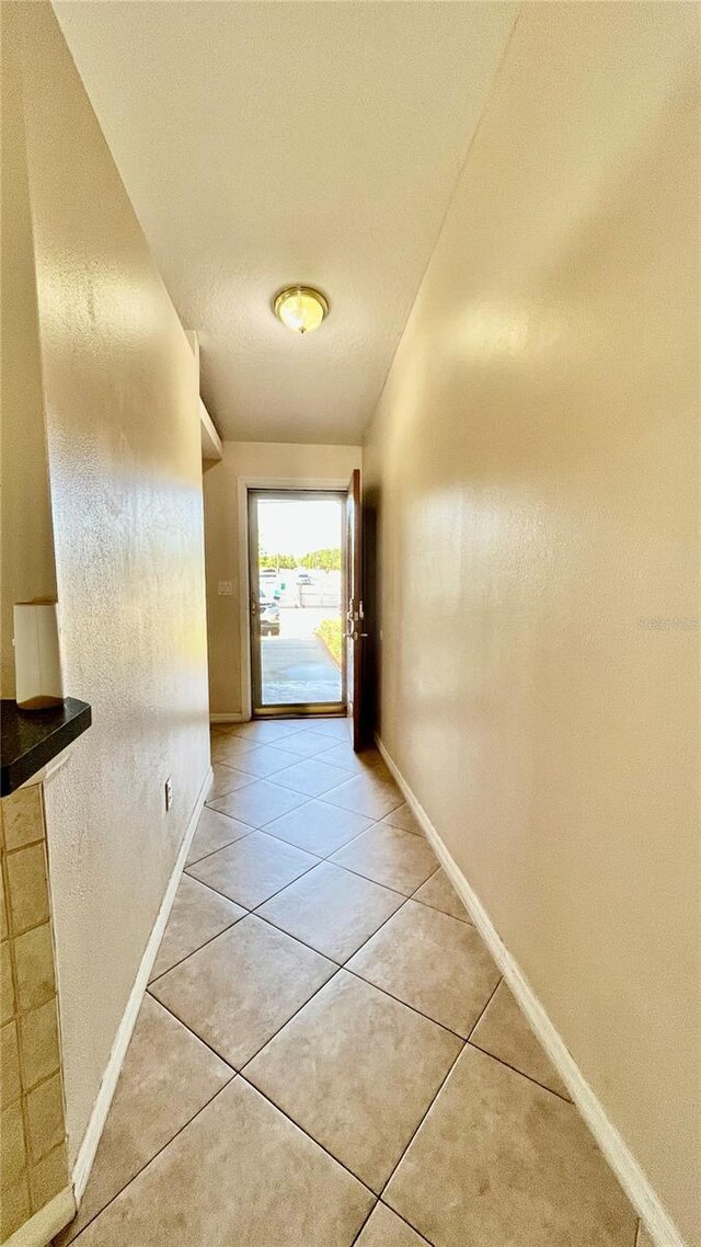 hallway featuring light tile patterned floors and baseboards