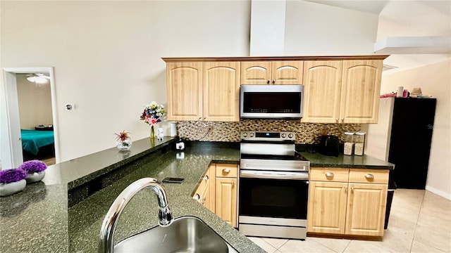 kitchen featuring a sink, decorative backsplash, light brown cabinetry, light tile patterned floors, and appliances with stainless steel finishes
