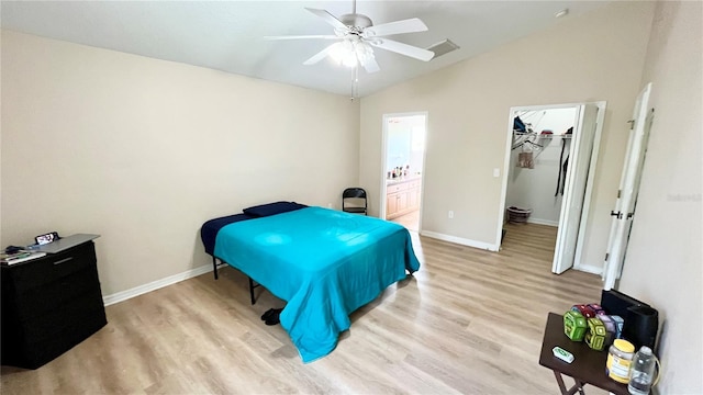 bedroom featuring lofted ceiling, ensuite bathroom, baseboards, and light wood-style floors