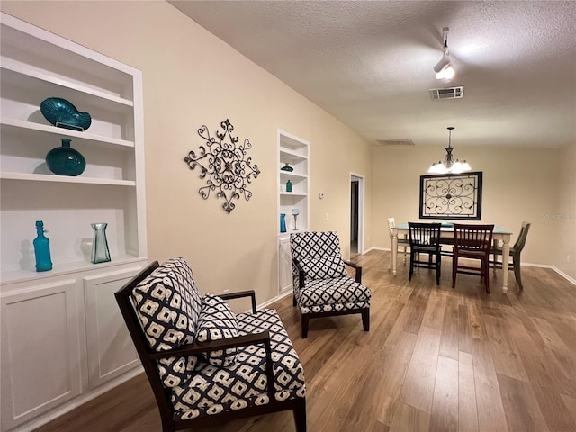 3907 Applegate Cir, Brandon, FL 33511 - living area featuring built in shelves, a chandelier, a textured ceiling, dark wood-type flooring, and rail lighting