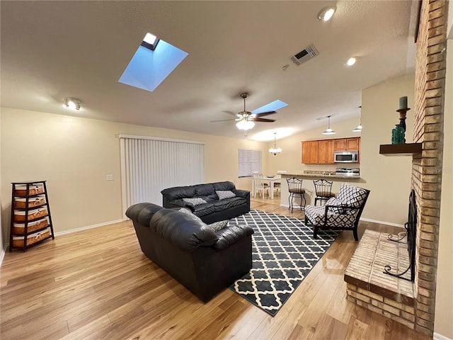 3907 Applegate Cir, Brandon, FL 33511 - living area featuring a skylight, light wood-type flooring, ceiling fan, a brick fireplace, and vaulted ceiling